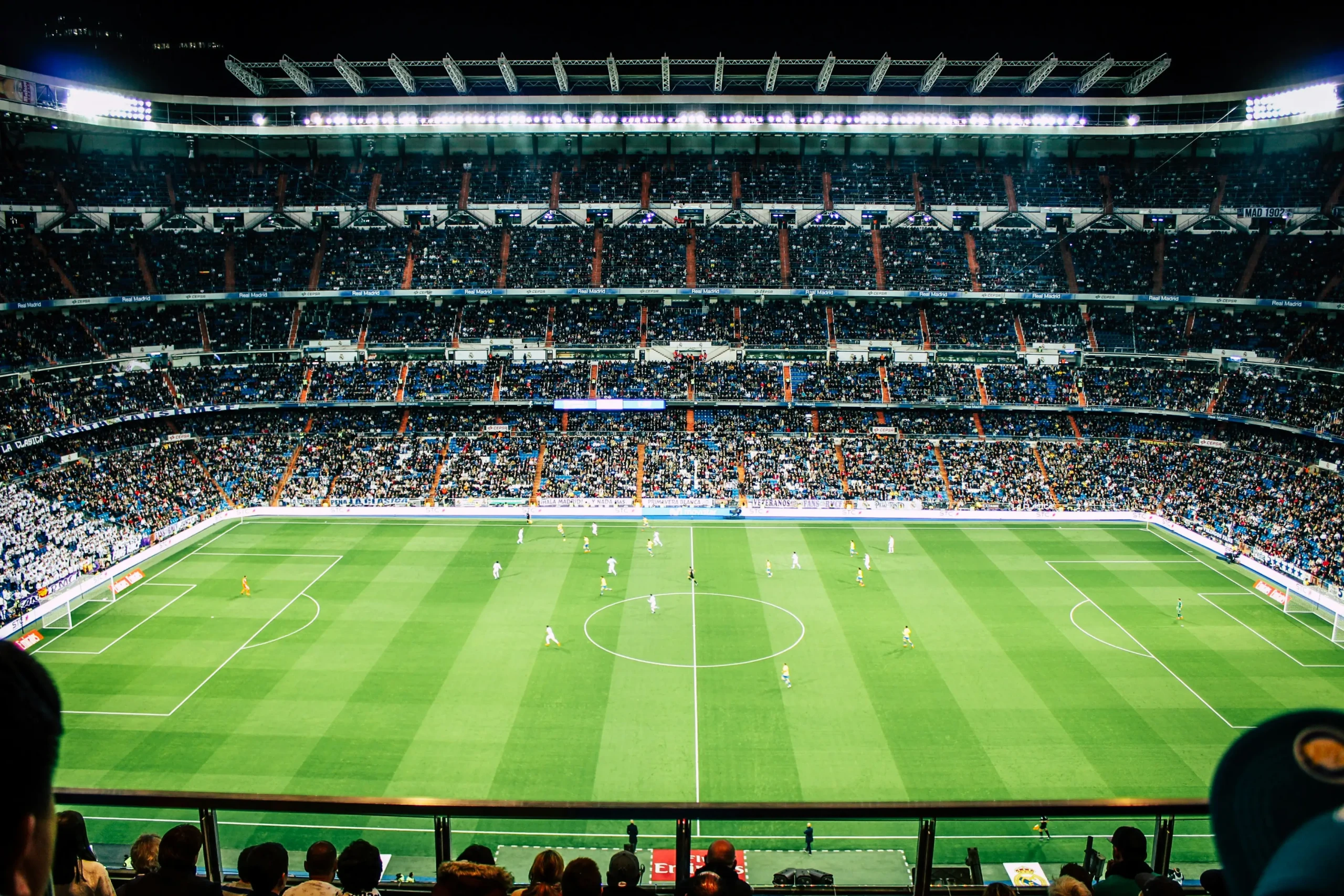 Wide view of a packed football stadium during a live match, showcasing large scale fan engagement and atmosphere